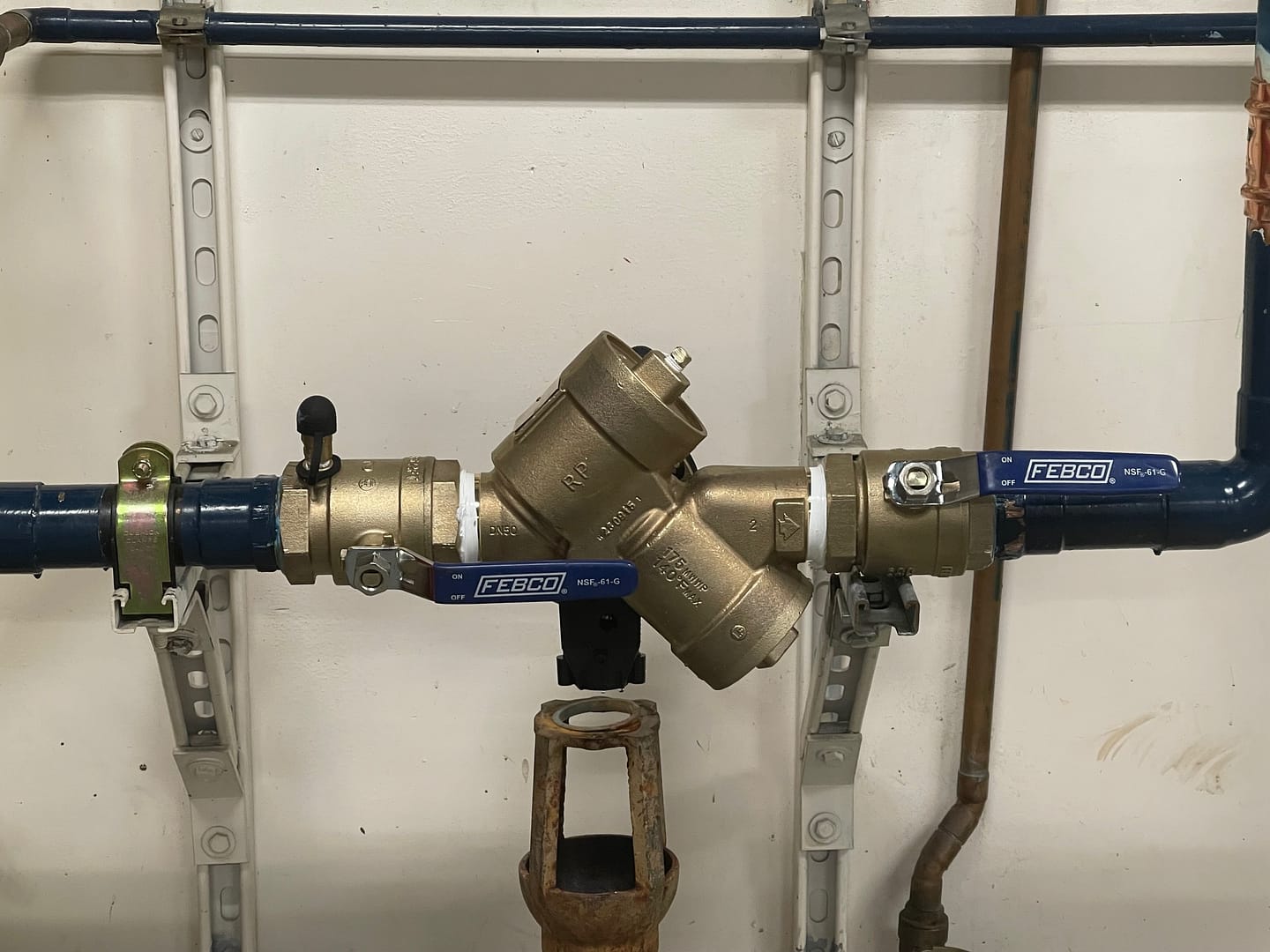 Image: A technician performing backflow testing in Morgan Hill, with testing equipment and valves visible against a backdrop of Morgan Hill's landscape.